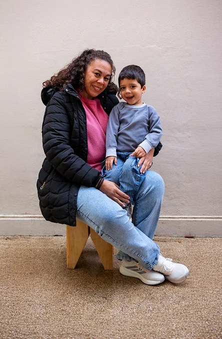 Bastian, paciente XLH sentado en el regazo de su mamá, ambos están sonriendo